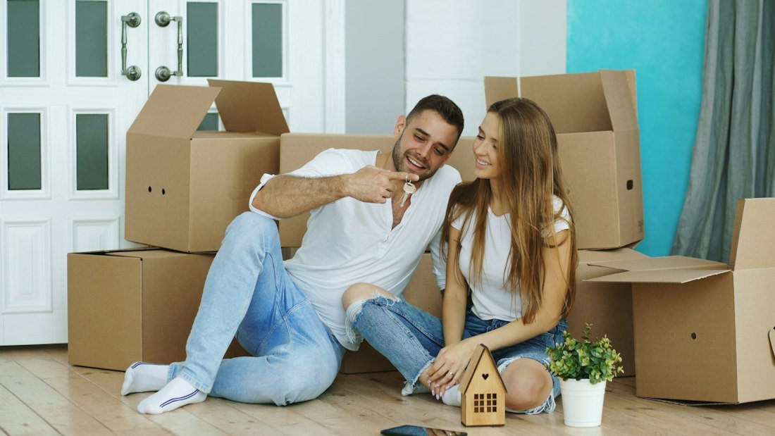 Couple assis parmi des cartons de déménagement dans un nouveau logement